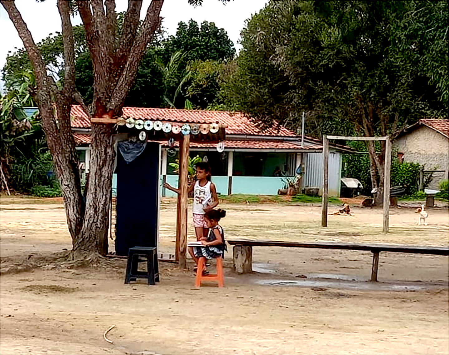 Criança sentadas em banco de madeira com livros.