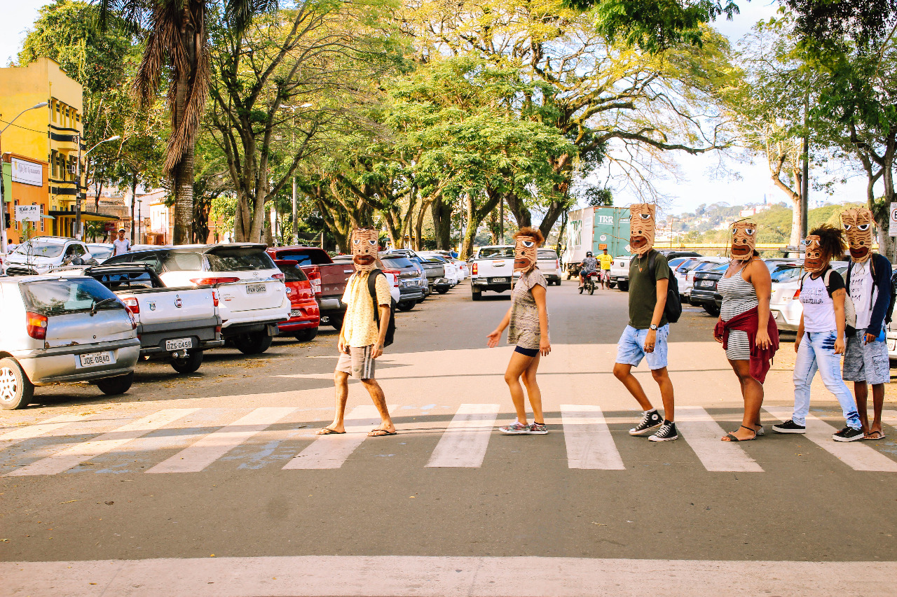 Pessoas atravessando a rua na faixa com sacos de papel na cabeça